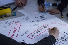 Foto: Teilnehmer eines Workshops beschriften Flipcharts.