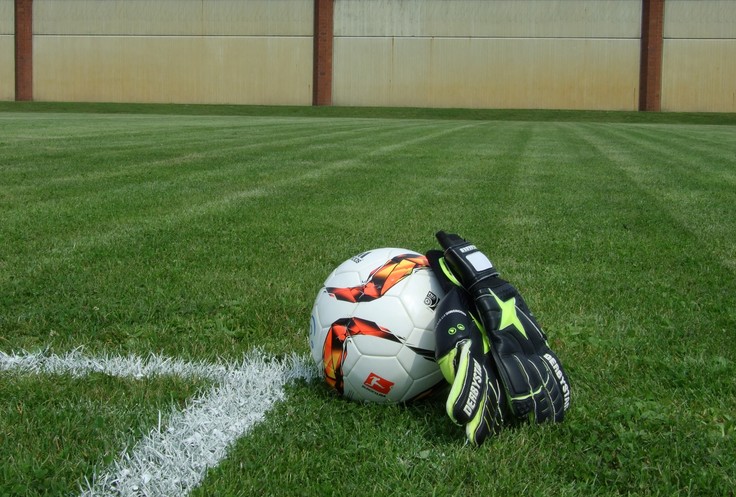 Foto von einem Fußball und Torwarthandschuhen auf dem Fußballplatz der JVA Uelzen