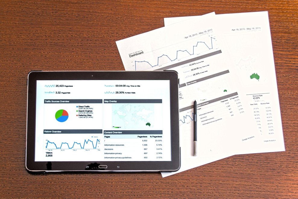 Foto: Tablet mit geöffneten Diagrammen und danebenliegenden ausgedruckten Statistiken